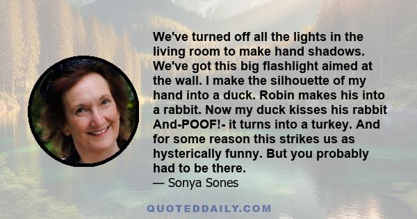 We've turned off all the lights in the living room to make hand shadows. We've got this big flashlight aimed at the wall. I make the silhouette of my hand into a duck. Robin makes his into a rabbit. Now my duck kisses